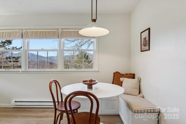 dining area featuring breakfast area, baseboard heating, and wood finished floors