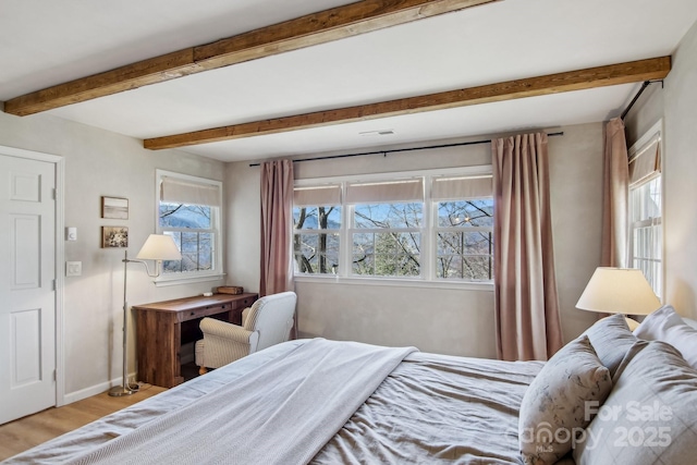 bedroom featuring light wood-style floors, visible vents, baseboards, and beam ceiling