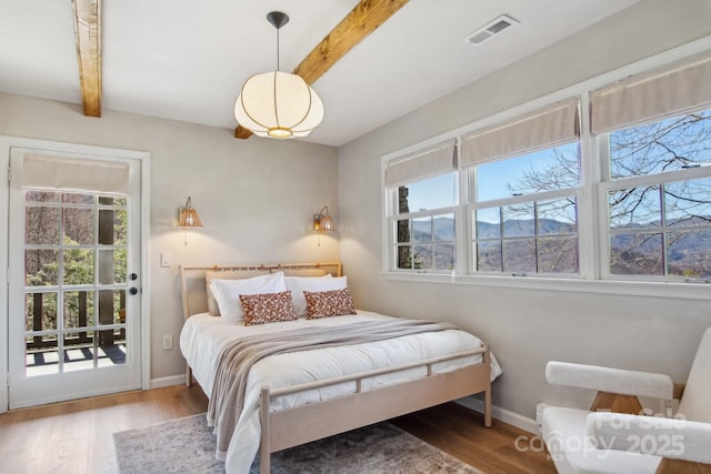 bedroom with baseboards, visible vents, beamed ceiling, and wood finished floors