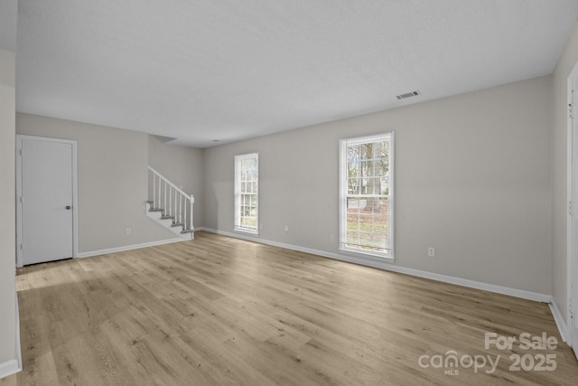 5948 Deveron Dr, Charlotte, NC 28211 - unfurnished living room featuring baseboards, stairs, visible vents, and light wood-type flooring