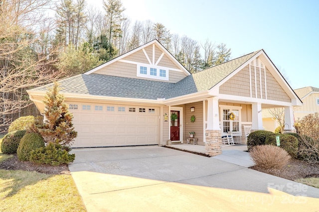 craftsman inspired home featuring an attached garage, a porch, concrete driveway, and roof with shingles