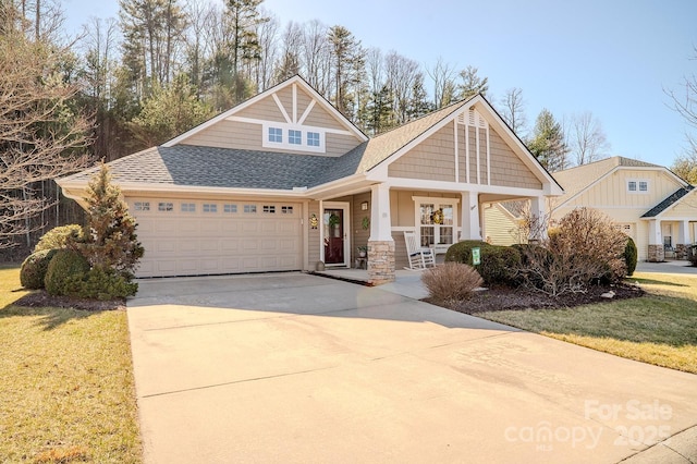 craftsman-style house featuring driveway, roof with shingles, an attached garage, a porch, and a front yard