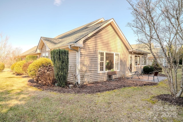 view of side of home featuring a yard and a patio