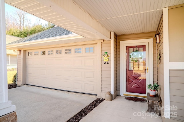 entrance to property featuring a garage, concrete driveway, and a shingled roof