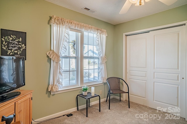 living area with visible vents, ceiling fan, light carpet, and baseboards