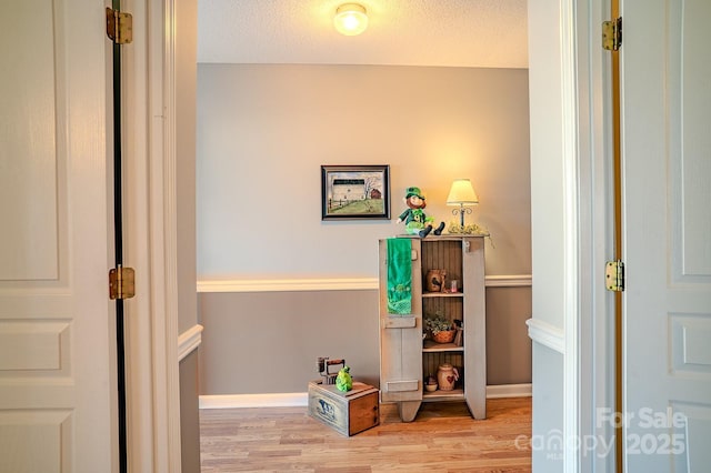 interior space with a textured ceiling, baseboards, and wood finished floors