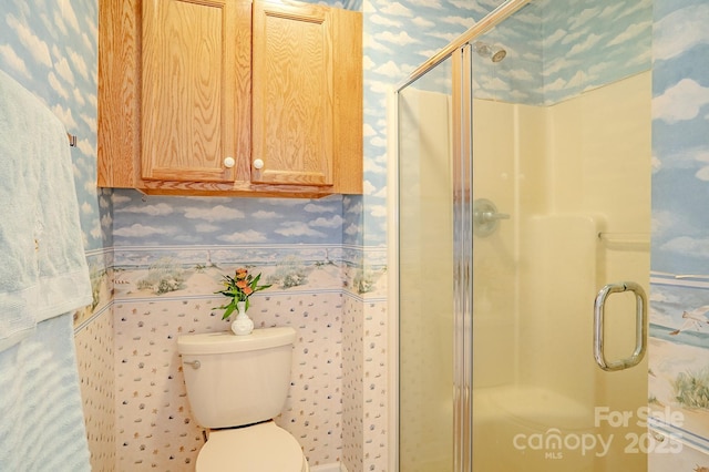 bathroom featuring a stall shower, toilet, and wallpapered walls