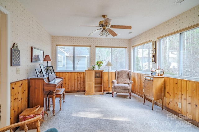 living area featuring a healthy amount of sunlight, wallpapered walls, a wainscoted wall, and light colored carpet