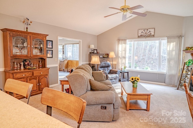 living room with lofted ceiling, light carpet, ceiling fan, and baseboards