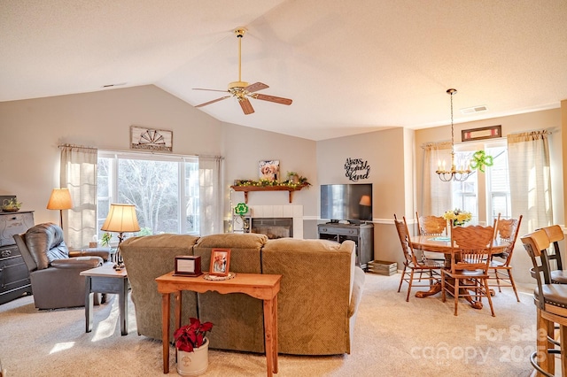 living area featuring light carpet, a fireplace, vaulted ceiling, and a wealth of natural light