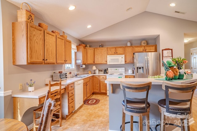 kitchen with white appliances, a sink, visible vents, light countertops, and a kitchen bar