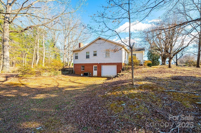 view of property exterior featuring a garage, driveway, central AC unit, a chimney, and brick siding