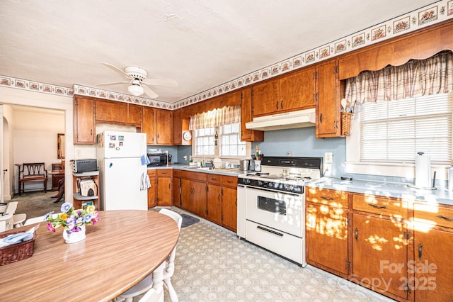 kitchen with white appliances, brown cabinets, light floors, light countertops, and under cabinet range hood