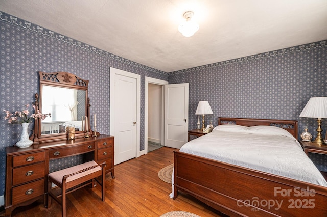 bedroom featuring wallpapered walls and wood finished floors