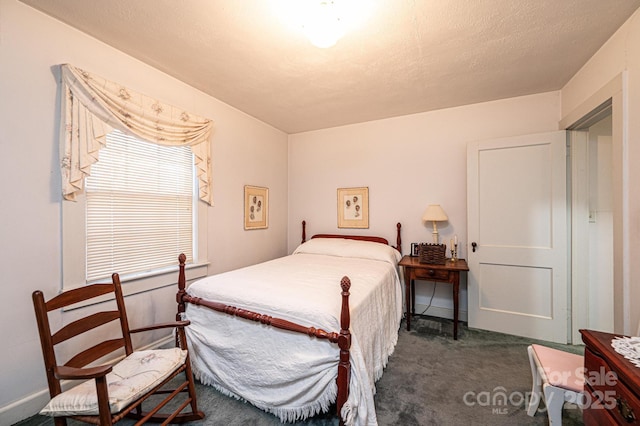 bedroom with a textured ceiling and dark carpet