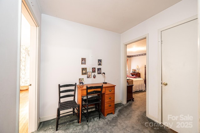 office space with dark colored carpet and baseboards