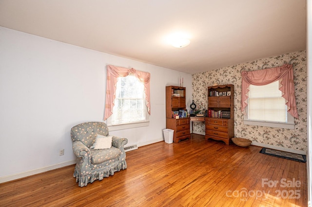 living area featuring baseboards, wood finished floors, and wallpapered walls