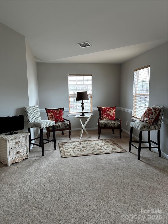 living area with light carpet, baseboards, and visible vents