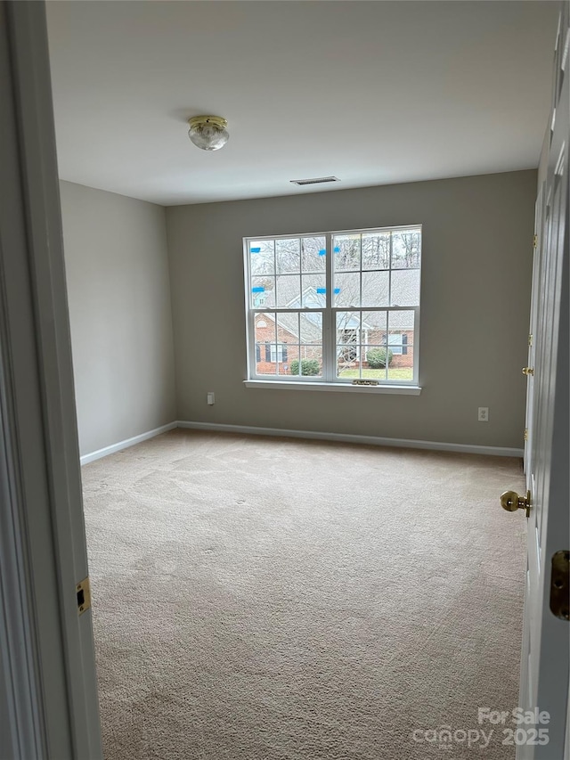 unfurnished room with light carpet and baseboards