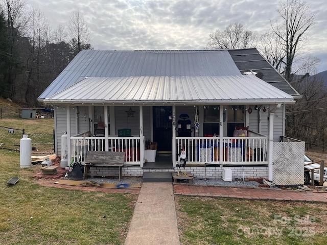 view of front of home featuring metal roof, fence, a porch, and a front yard