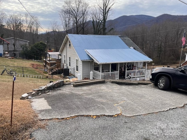 view of front facade featuring central air condition unit, covered porch, a mountain view, and metal roof