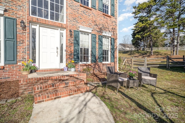 doorway to property with brick siding and fence