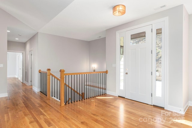 entrance foyer with wood finished floors, visible vents, and baseboards