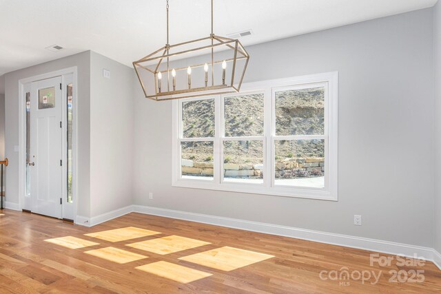 unfurnished dining area featuring wood finished floors, visible vents, and baseboards