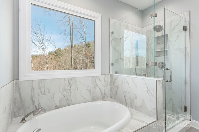 full bathroom with a marble finish shower and a bath