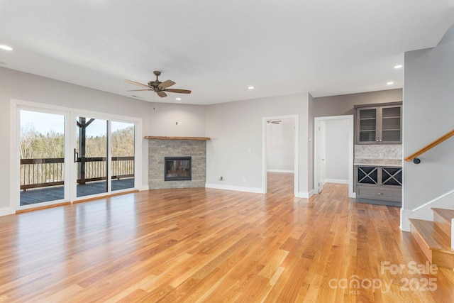 unfurnished living room featuring recessed lighting, a fireplace, stairway, and wood finished floors