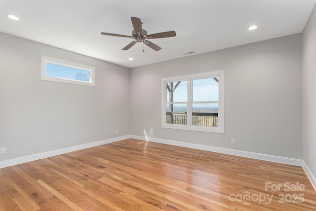 spare room featuring baseboards, a healthy amount of sunlight, visible vents, and light wood finished floors