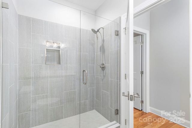 bathroom with a stall shower and wood finished floors