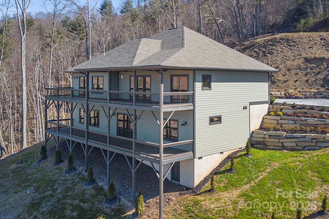 back of house featuring a shingled roof, crawl space, a yard, and a balcony