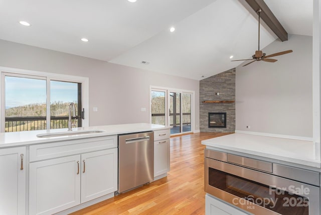 54 Herron View Ln, Weaverville, NC 28787 - kitchen featuring stainless steel appliances, light wood finished floors, a stone fireplace, ceiling fan, and white cabinets