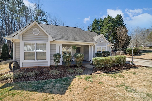 view of front of property featuring covered porch, roof with shingles, and a front lawn