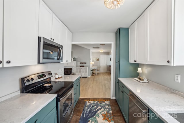 kitchen with appliances with stainless steel finishes, dark tile patterned flooring, white cabinets, and baseboards