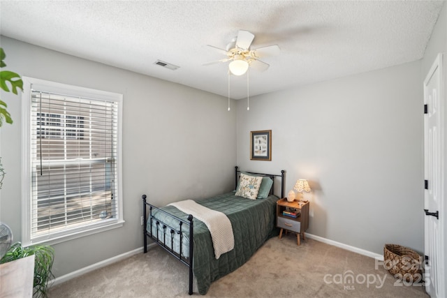 carpeted bedroom with a ceiling fan, baseboards, visible vents, and a textured ceiling