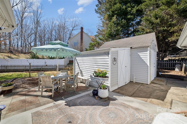 view of patio / terrace featuring outdoor dining space, a fenced backyard, and an outdoor structure