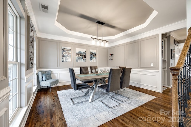 dining area with dark wood finished floors, a raised ceiling, visible vents, and a decorative wall