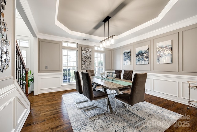 dining room featuring dark wood finished floors, a raised ceiling, a decorative wall, and stairway