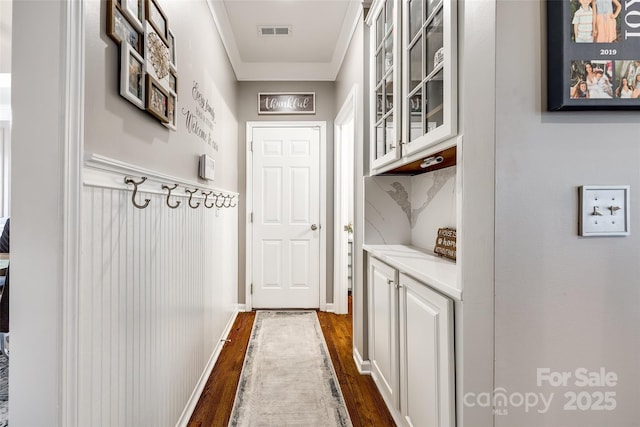 entryway featuring ornamental molding, dark wood-type flooring, and visible vents