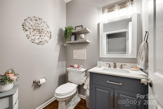 bathroom with toilet, baseboards, wood finished floors, and vanity