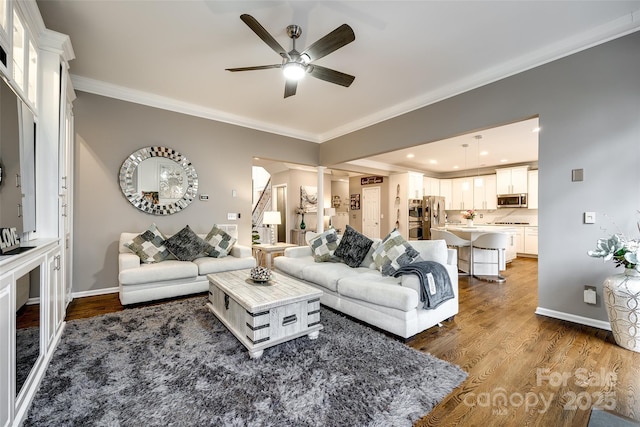 living area with baseboards, wood finished floors, and crown molding