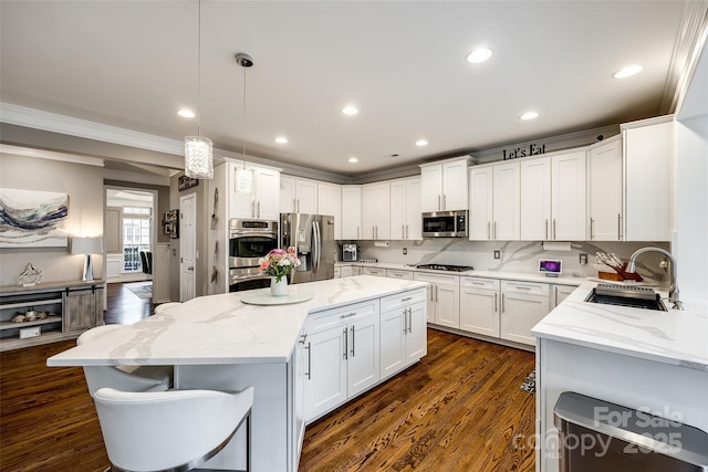 kitchen with light stone counters, pendant lighting, appliances with stainless steel finishes, white cabinets, and a kitchen island