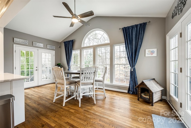 dining space featuring ceiling fan, high vaulted ceiling, french doors, and wood finished floors