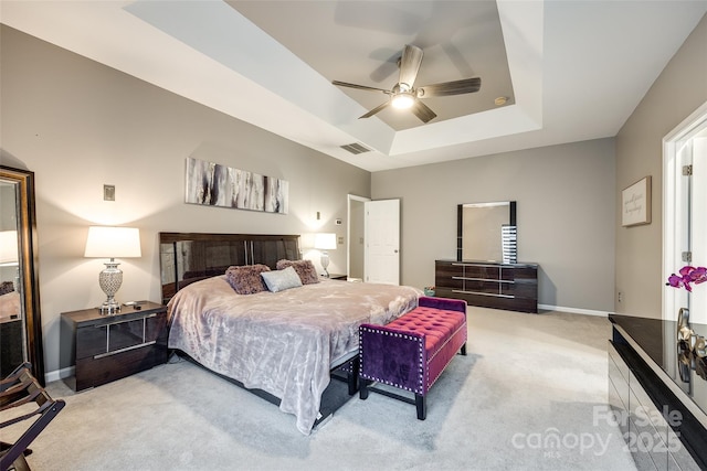 bedroom featuring carpet floors, a raised ceiling, visible vents, ceiling fan, and baseboards