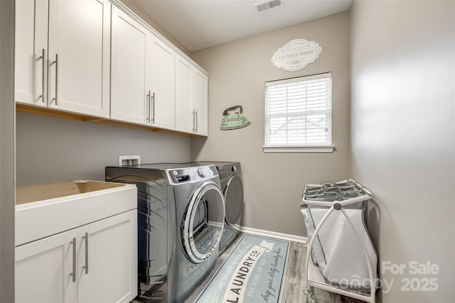 washroom featuring cabinet space, visible vents, wood finished floors, washer and dryer, and baseboards