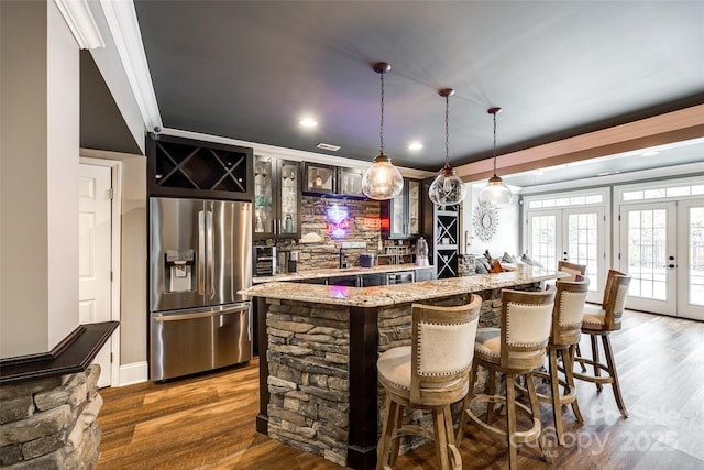 bar featuring stainless steel fridge with ice dispenser, wet bar, crown molding, french doors, and pendant lighting