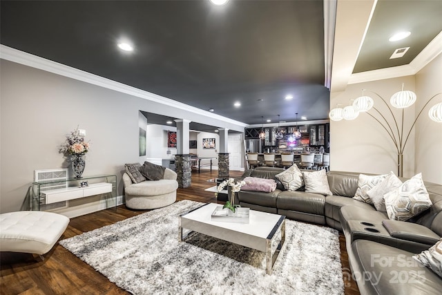 living room featuring dark wood-style floors, recessed lighting, visible vents, ornamental molding, and ornate columns