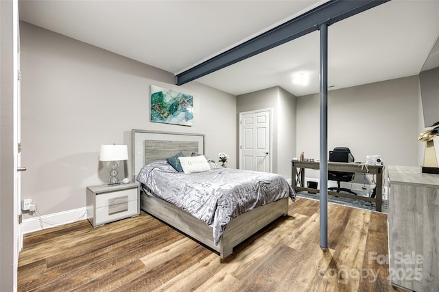 bedroom featuring baseboards, wood finished floors, and beamed ceiling